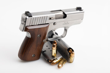 Automatic hand gun with wooden grip and bullet magazines on white background , Pocket gun