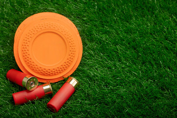 Naklejka premium Clay disc flying targets and shotgun bullets on green grass background ,Clay Pigeon target