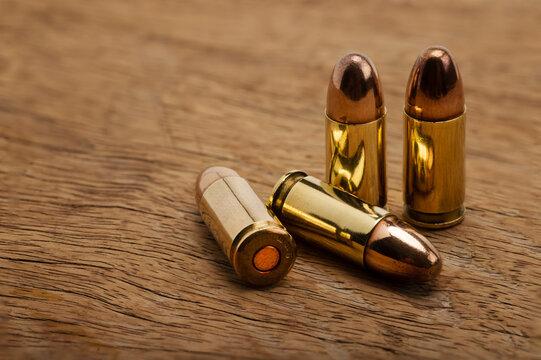 9 mm gun ammunition on wooden background , hollow point and full jacket bullets