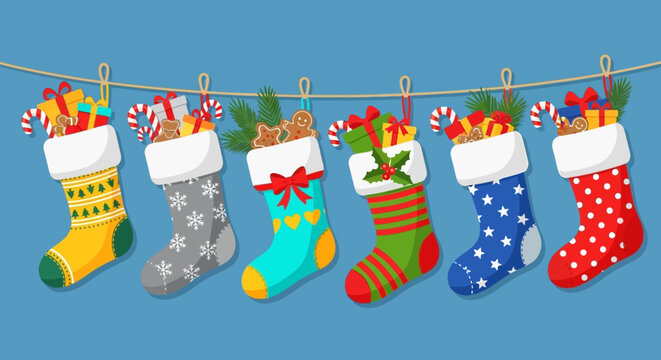 Festive Christmas stockings filled with gifts, candy canes, and holiday treats hanging on a string against a blue background