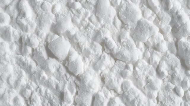 Close-up view of a fine white powdery substance, potentially baking soda or flour, showing its granular texture and subtle shadows