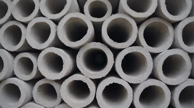 Close-up view of a stack of concrete pipes, showcasing their circular openings and textured surfaces