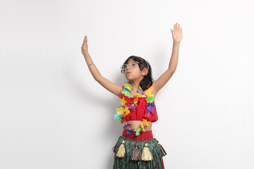 5-year-old Latina girl with brown hair enjoys learning to dance Hawaiian, wearing a colorful skirt and leis, and shows off her moves
