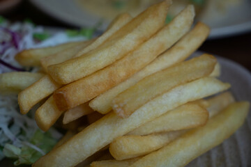 A close-up shot of golden, crispy French fries served on a plate with a side of shredded cabbage.