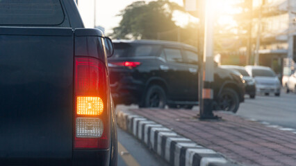 Rear side of pickup car black color with turn on signal right. Park to wait for a U-turn. Car in front is about to make a U-turn. Blurred of many cars are driving by.