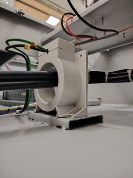 Image of a toroidal current transformer mounted inside a electrical enclosure.