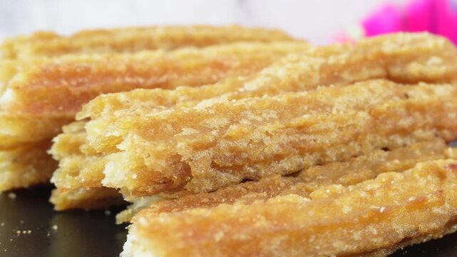 Black rotating plate with churros with cinnamon and sugar, Mexican food