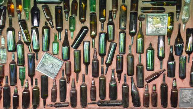 Recycled glass bottles embedded in wall creating unique texture.