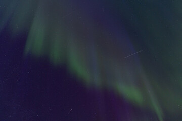 Curtains of green light and magenta hues merge in the vertical display of the Northern Lights, highlighting the densely scattered stars in the dark sky
