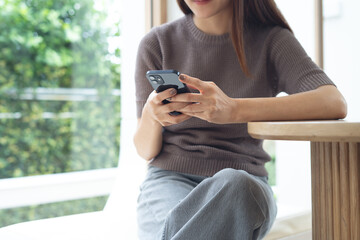 Young asian woman sitting at table using smartphone in coffee shop. social media network, online messaging and chatting on mobile app, people, lifestyle, closeup
