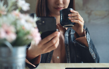 Woman using smartphone and drinking coffee at coffee shop. modern people lifestyle