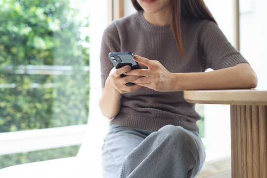 Young asian woman sitting at table using smartphone in coffee shop. social media network, online messaging and chatting on mobile app, people, lifestyle, closeup