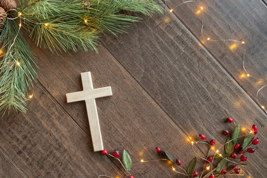 cross with frame of evergreen and red berries with lights