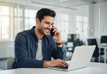 Smiling businessman talking on phone while working on laptop in modern office