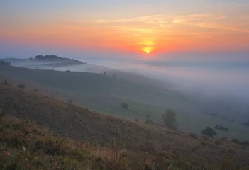 Obraz premium Vibrant sunrise and morning fog covering rolling hills