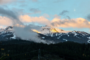 Snowy Mountain Range at Dusk in British Columbia, Clouds Rolling Over Pines, Moon In Sky