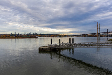 Fototapeta premium Scenic Riverfront View With City Skyline, Bridge, And Pier In New Westminster, BC, Canada