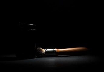 Naklejka premium Artistic paintbrush on dark background with spotlight and dramatic lighting