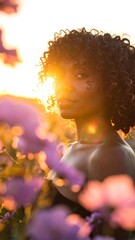 Portrait of a woman with curly hair, bathed in golden sunlight. She?s surrounded by blurred lavender flowers, looking over her shoulder