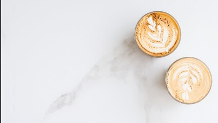 Two overhead cups of latte art coffee on a white marble surface cappuccino espresso