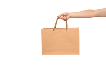 A person's hand holding a paper shopping bag with handles on a clean white background. Studio shot with ample copy space for text, logos, or branding. Isolated on white, cut out.
