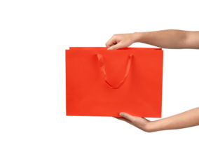 A person's hand holding a paper shopping bag with handles on a clean white background. Studio shot with ample copy space for text, logos, or branding. Isolated on white, cut out.