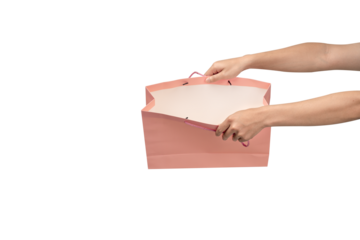 A person's hand holding a paper shopping bag with handles on a clean white background. Studio shot with ample copy space for text, logos, or branding. Isolated on white, cut out.