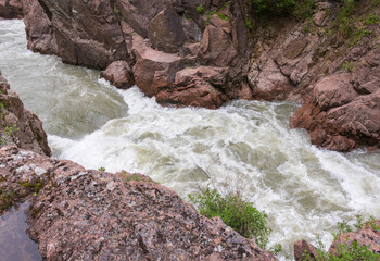 A narrow gorge through which a river flows, the sun's rays break through the foliage
