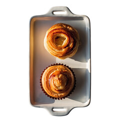 Two Golden Brown Swirled Pastries with Glaze on a White Rectangular Baking Dish with Handles Bathed in Warm Sunlight