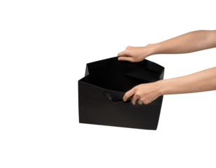 A person's hand holding a paper shopping bag with handles on a clean white background. Studio shot with ample copy space for text, logos, or branding. Isolated on white, cut out.