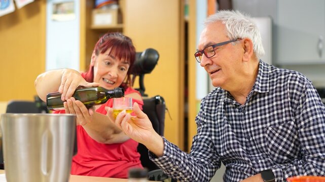 Woman with disability pouring olive oil with senior man