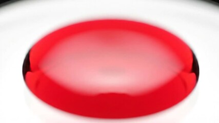 Close Up Macro Shot Of A Red Liquid Droplet Falling And Splashing In Slow Motion Against A Clean White Background Creating Ripples - Powered by Adobe
