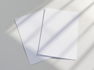 Two blank white paper sheets overlapping with soft daylight