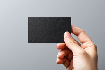 A hand holds a blank black business card