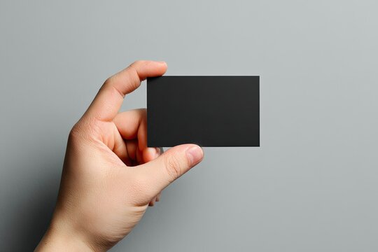 Hand holding a blank black business card (1) - Powered by Adobe