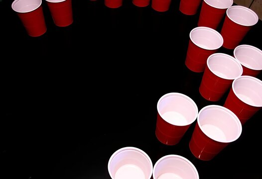 Red solo cups arranged in a beer pong triangle on a black surface,   games,  alcohol