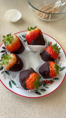 Chocolate covered strawberries on ceramic saucer. Handmade dessert. Holidays and decorations, food.