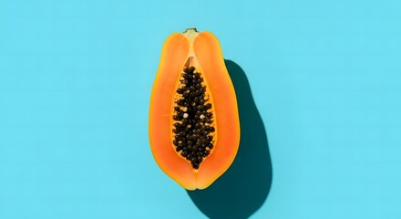 Vibrant half papaya fruit with black seeds showcased against a bright teal background