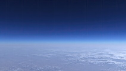 High-altitude view of Earth's atmosphere.  Pale clouds blanket the lower portion. Deep blue sky above.  Horizon clearly defined