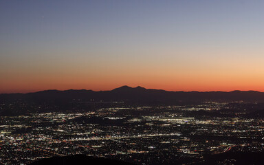 Fototapeta premium sunset mountain silhouette at dawn with city light