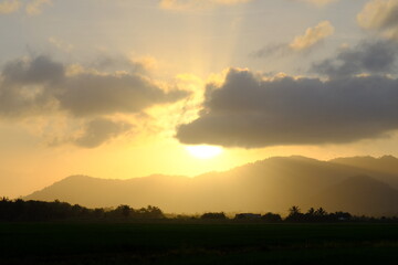 Obraz premium Dramatic Sunshine Burst over Hills and Paddy Field