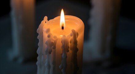 A close-up of a lit candle with melting wax and a warm flame in a dark environment, creating a peaceful and calming atmosphere