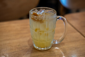 A glass of plum soda, on the wooden table