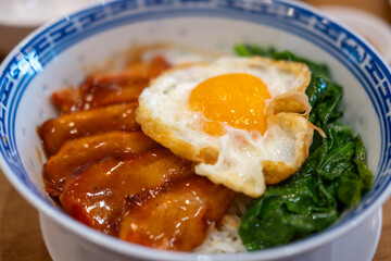 Barbecued red pork in sauce with rice, and fried egg on the top.