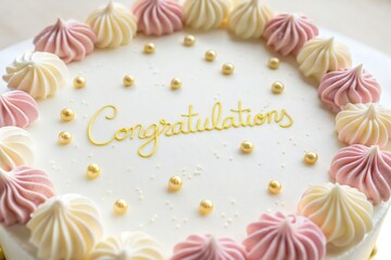 Beautifully decorated cake with 'Congratulations' message and pastel meringue swirls