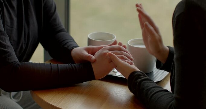 white women holding hands across table during rehearsal, close-up of palms and cups, supportive rehearsal of vows and promises, gentle gestures, quiet emotional preparation in cafe setting