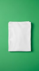 A neatly folded white fabric piece placed on a vibrant green background for display or product presentation purposes