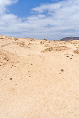 A bright, sunny day on La Graciosa with sandy dunes and a beautiful blue sky with clouds.