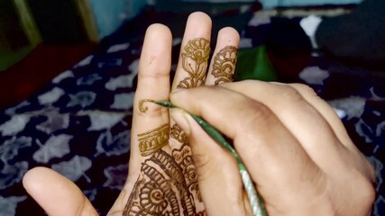 A closeup video of a girl applying henna tattoo on her hands on wedding or marriage function day. Girls apply henna design on hands during wedding ceremony or marriage functions. Henna design on hands