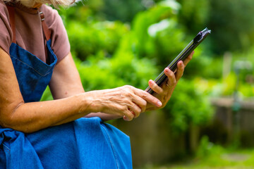 Senior woman using digital tablet for gardening planning outdoors